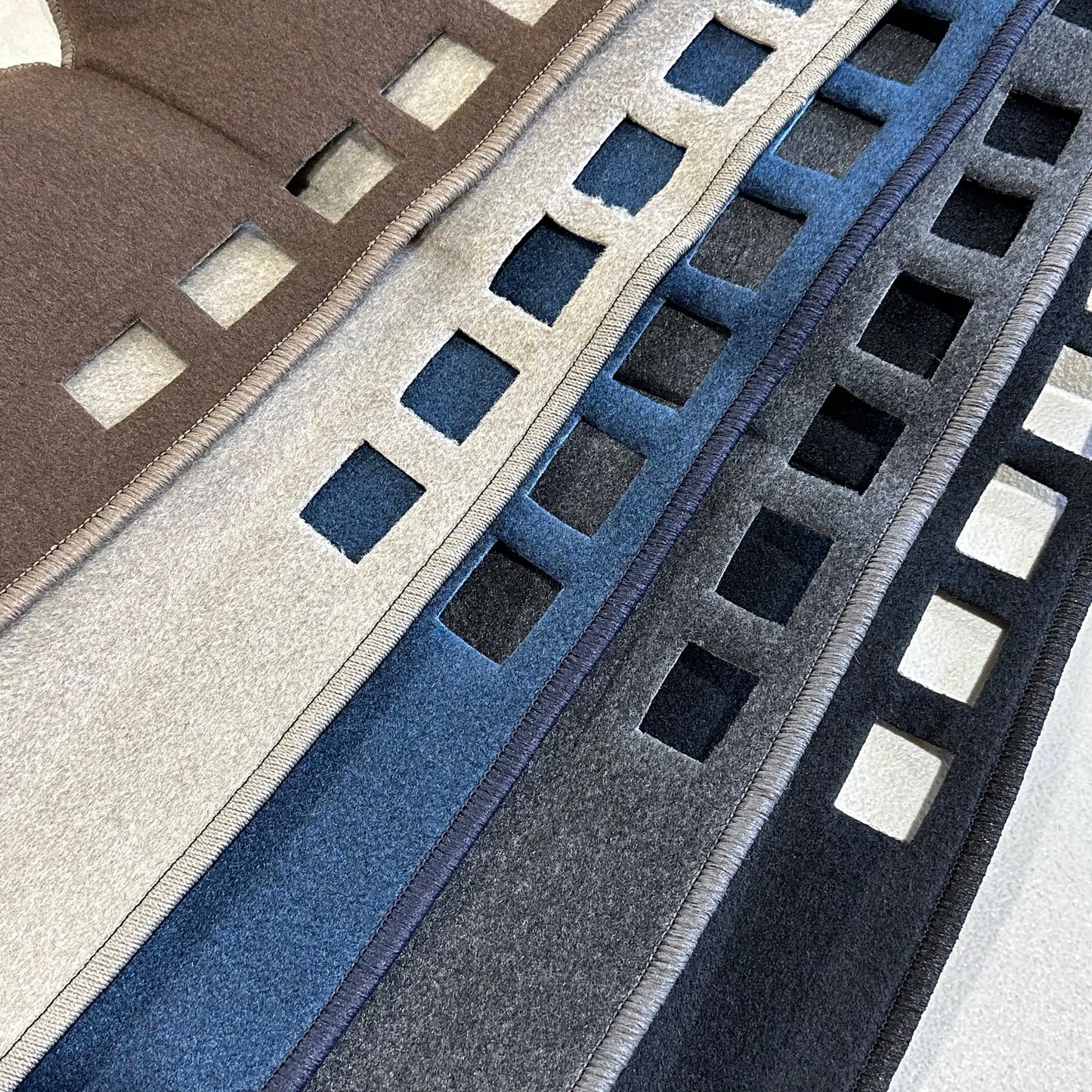 Close-up of textured carpet strips in brown, gray, blue, and black.