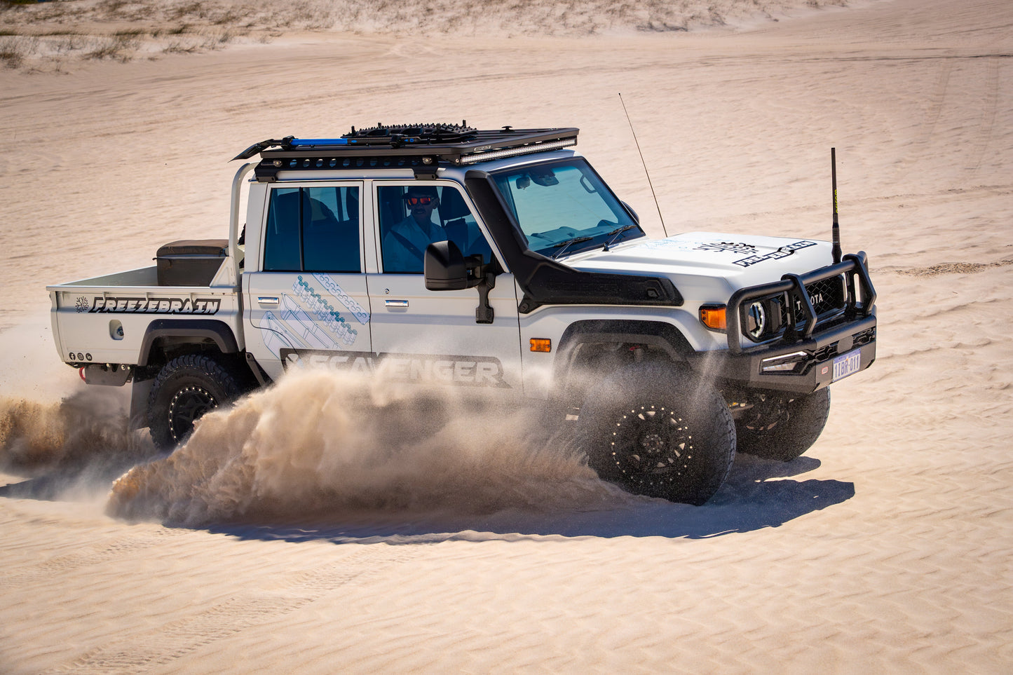 Off-road vehicle driving through sand in a desert setting