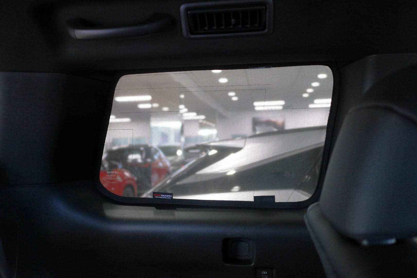 Car sun visor with a reflective surface showing a car showroom interior.