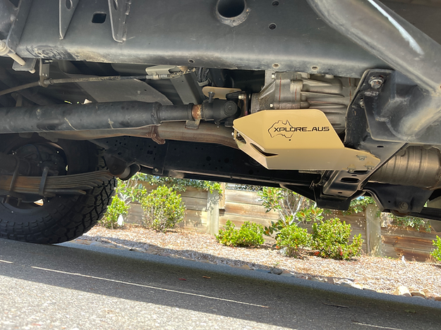 Undercarriage of a vehicle with a gold Xplore AUS guard on a road.