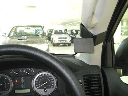 Car interior with a rearview mirror and dashboard view of a parking lot.