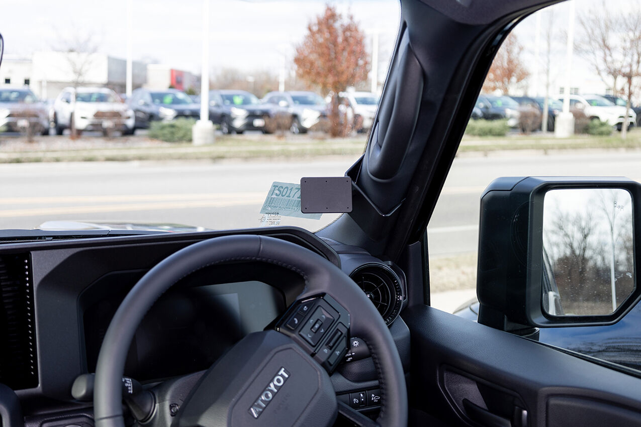 Close-up of a car's interior with steering wheel and dashboard, showing the brand 'TOYOTA'.