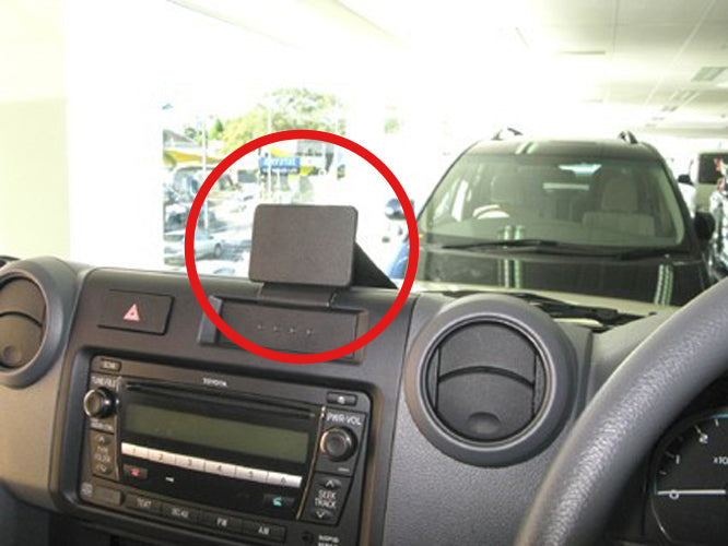 Car dashboard with a smartphone mount and a red circle around it, with a car  in the background.