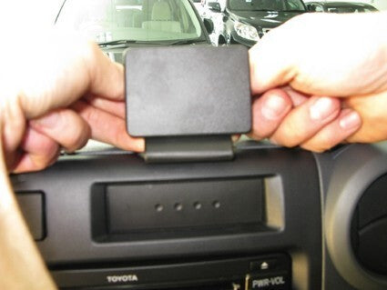 Person installing a car mount on a Toyota vehicle's dashboard.
