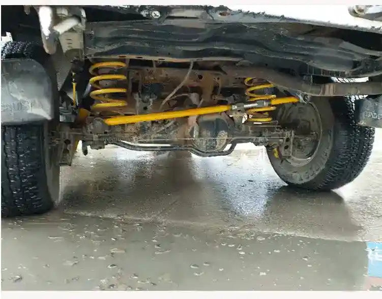 Close-up of a vehicle's undercarriage with suspension components on a concrete floor.