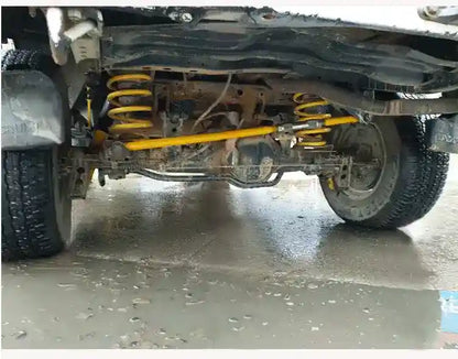 Close-up of a vehicle's undercarriage with suspension components on a concrete floor.