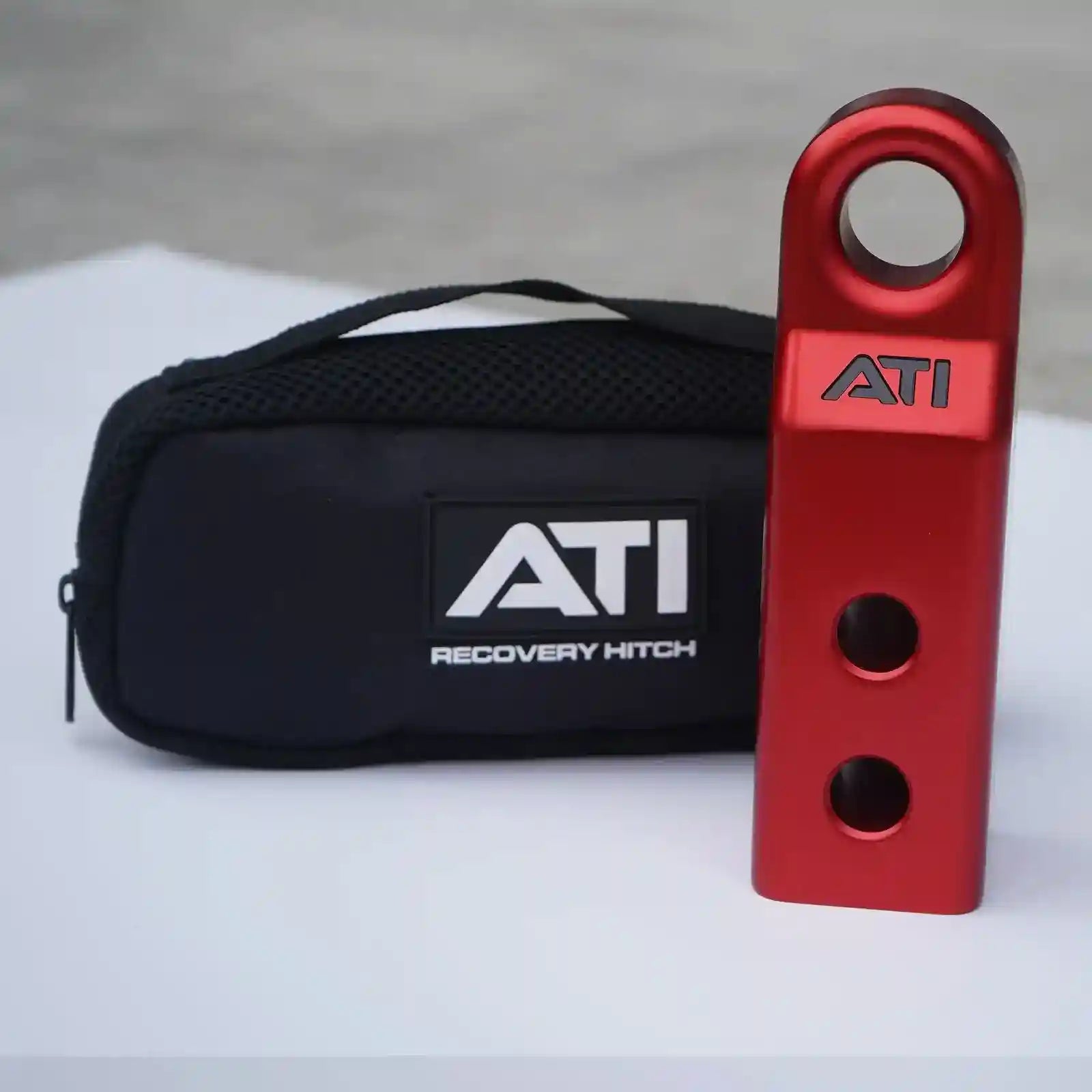 Red ATI recovery hitch and black carrying case on a light gray background