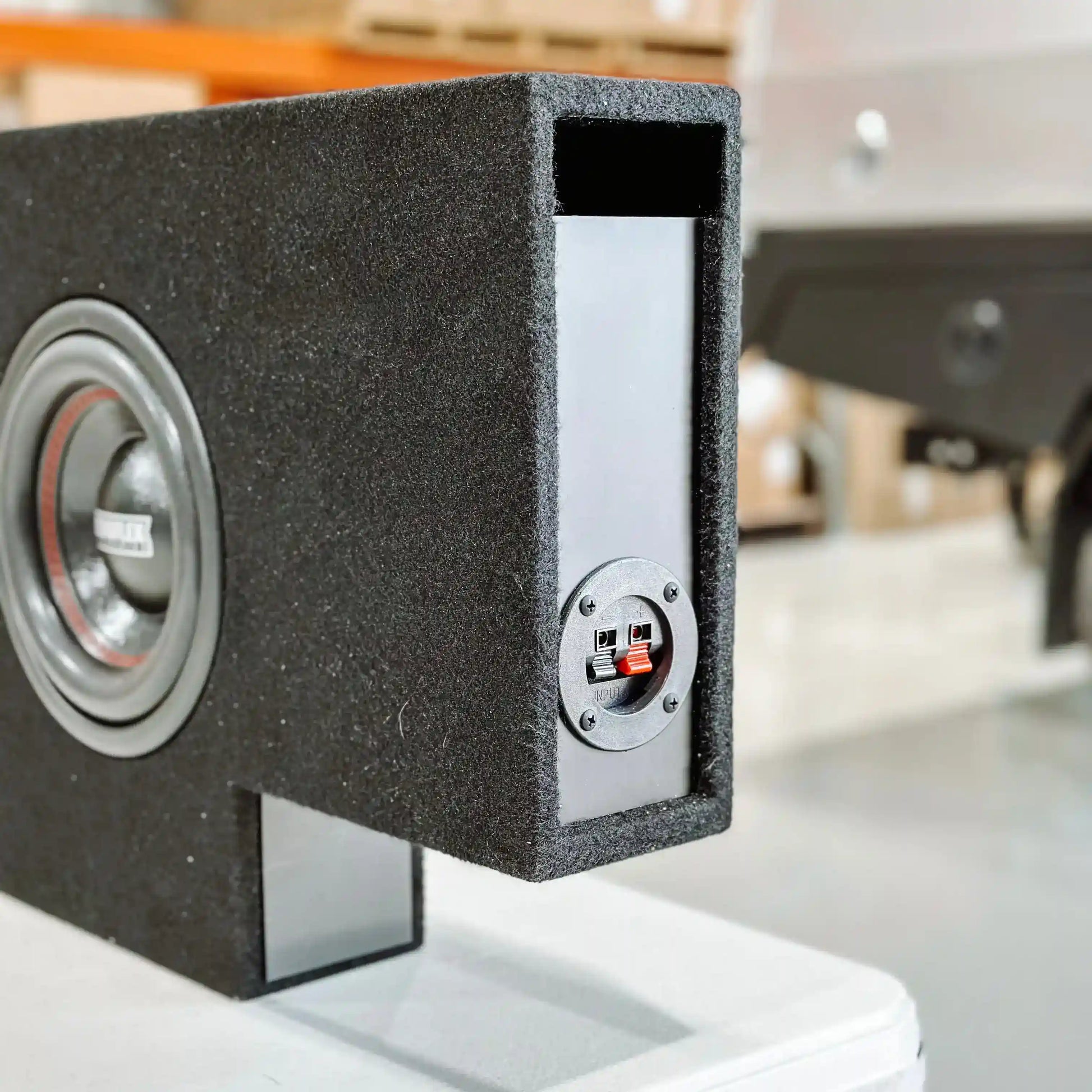Car subwoofer enclosure with speaker and control panel on a blurred background