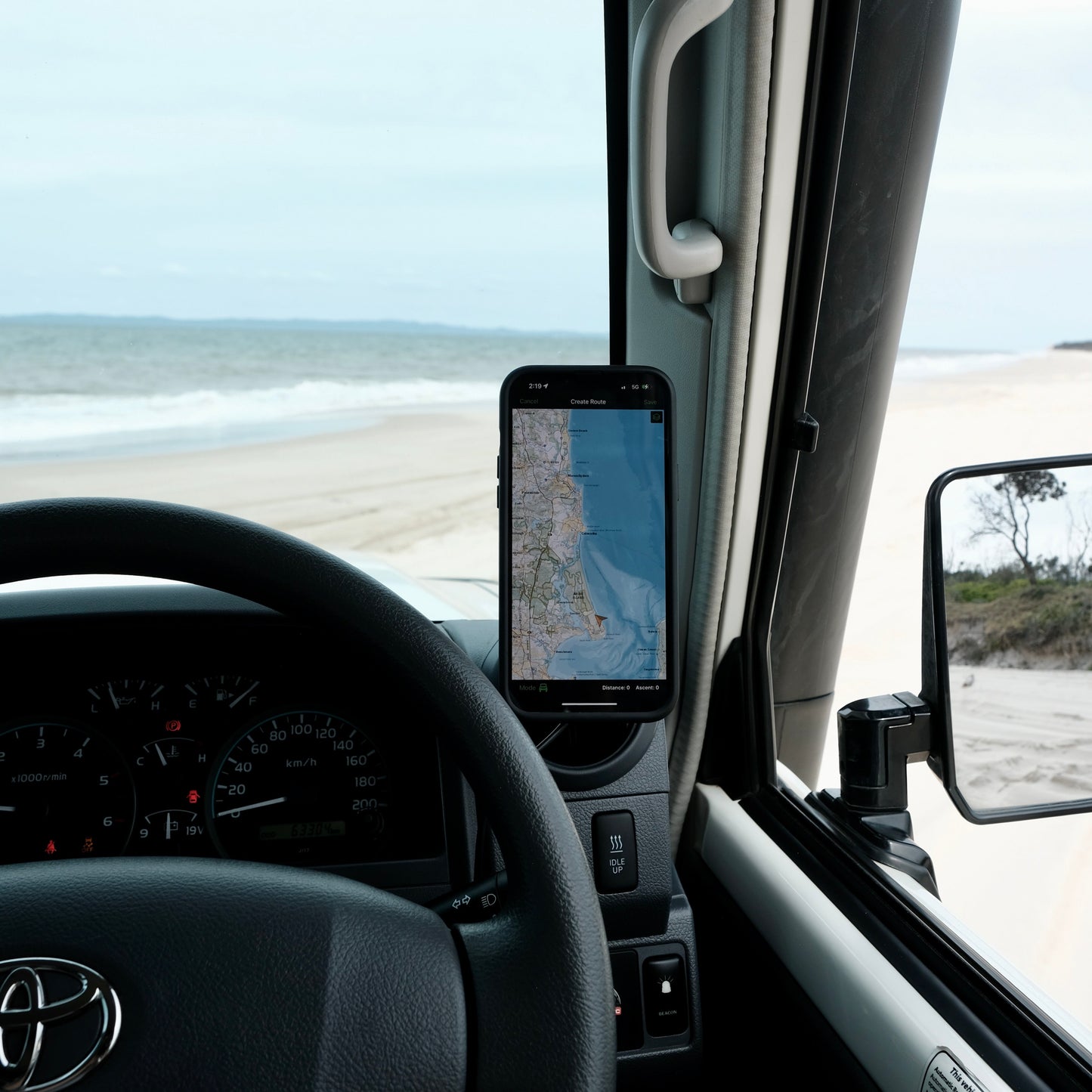 Car interior with a smartphone displaying a map, beach view outside