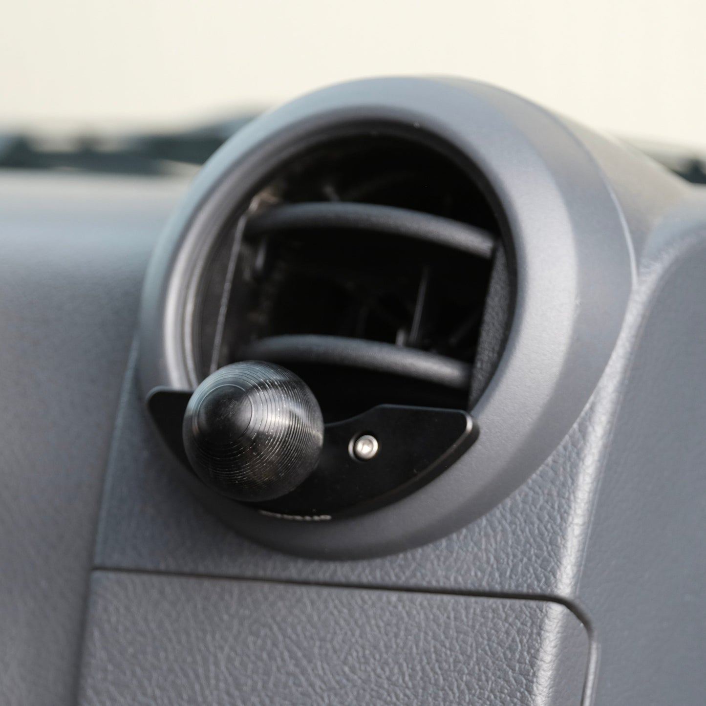 Car air vent with phone mount on a gray dashboard