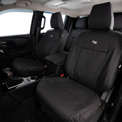 Black car seat covers with a logo on the backrest in a vehicle interior.