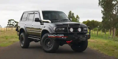 Black off-road vehicle with 'Macher' branding on a rural road.