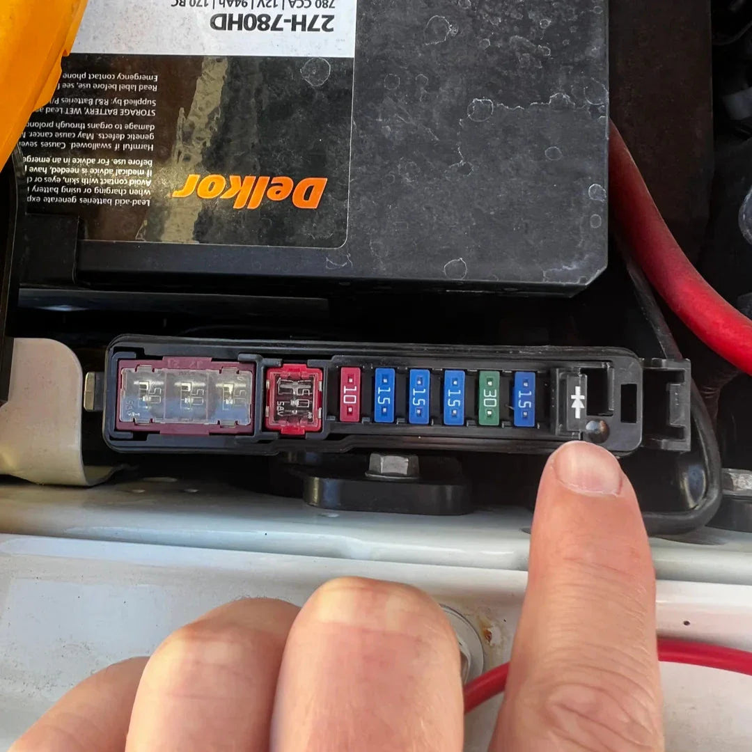 Car fuse box with Alternator Booster Diode and a finger pointing at it.