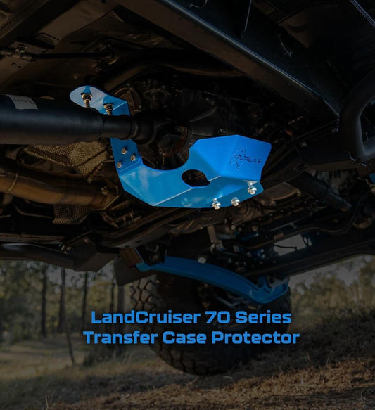 Blue transfer case protector on a LandCruiser 70 Series vehicle, with a blurred natural background.