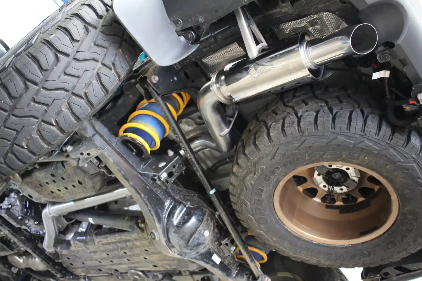 Close-up of a vehicle's suspension system with tires and exhaust pipe.
