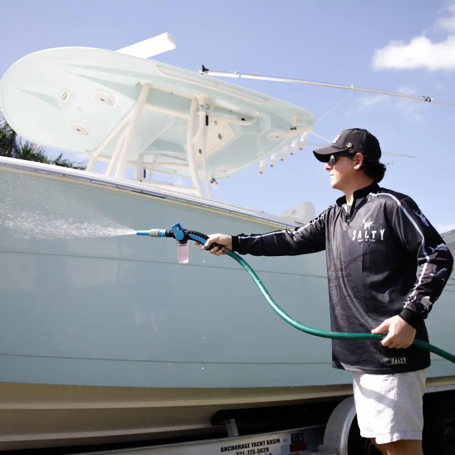 Man cleaning a boat with a hose on a sunny day