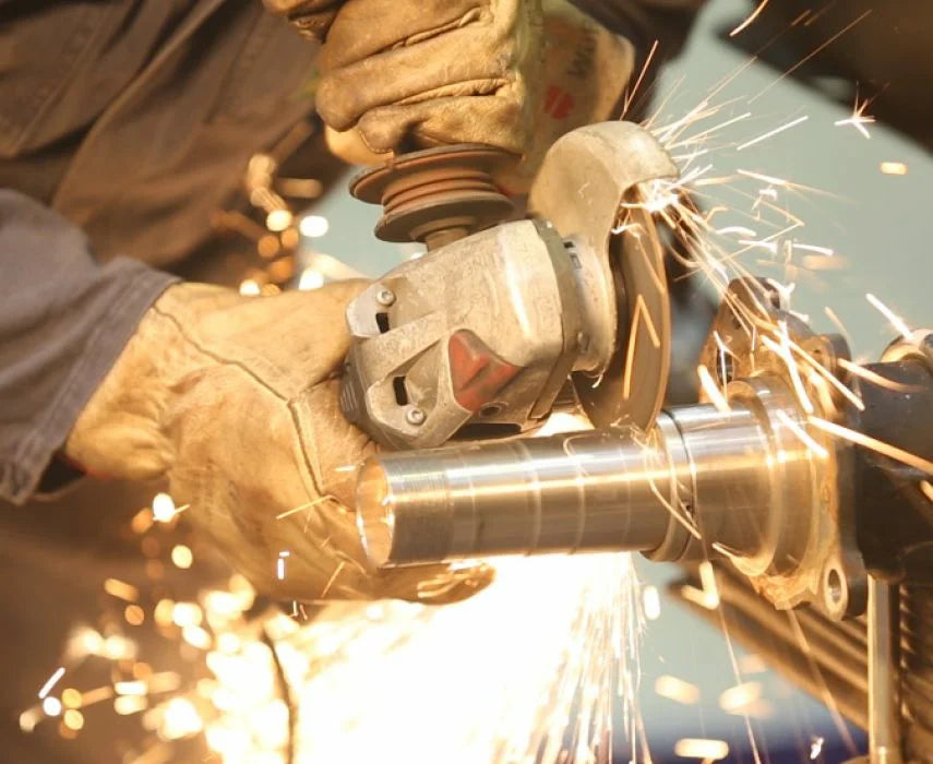 Person using a grinder with sparks flying, indicating metalworking or construction activity.