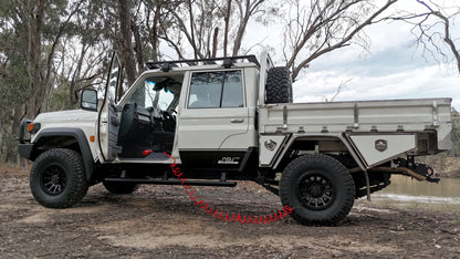 White off-road vehicle with a flatbed on a dirt road surrounded by trees.
