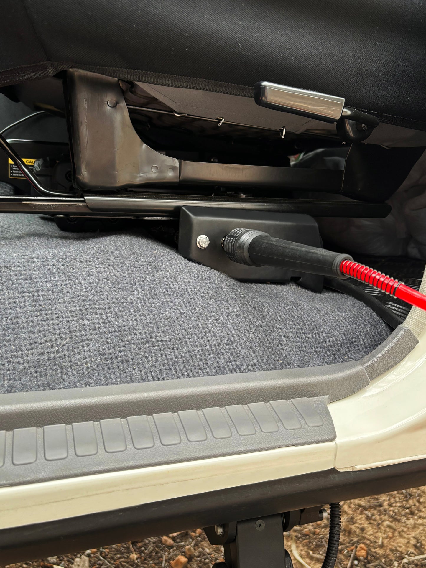 Car seat with a power outlet and cable attached, showing a close-up of the interior.