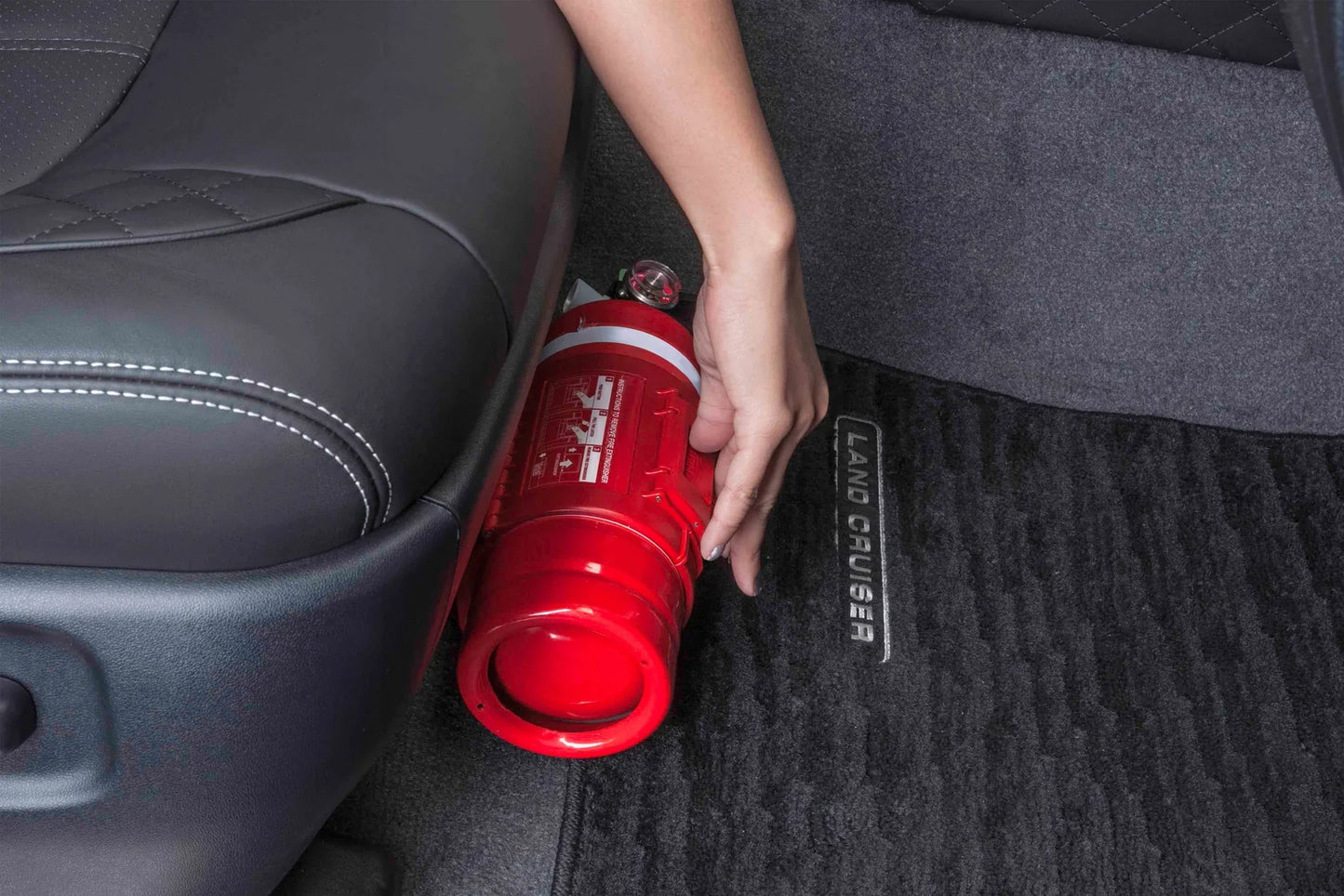 Person holding a red fire extinguisher in a car.