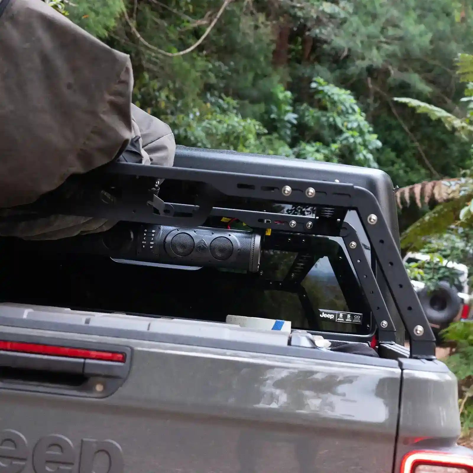 Back of a Jeep with an open tailgate and roof rack in a forest setting