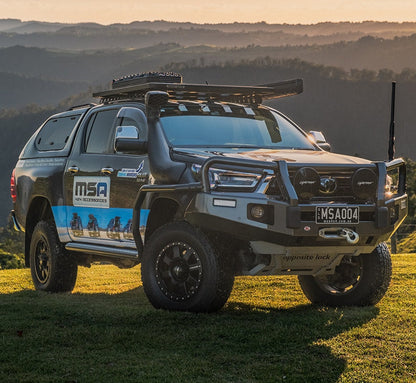 Toyota Hilux with MSA branding on a grassy field with mountains in the background