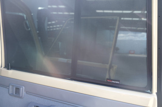 Window of a vehicle with a reflection and visible brand logo.