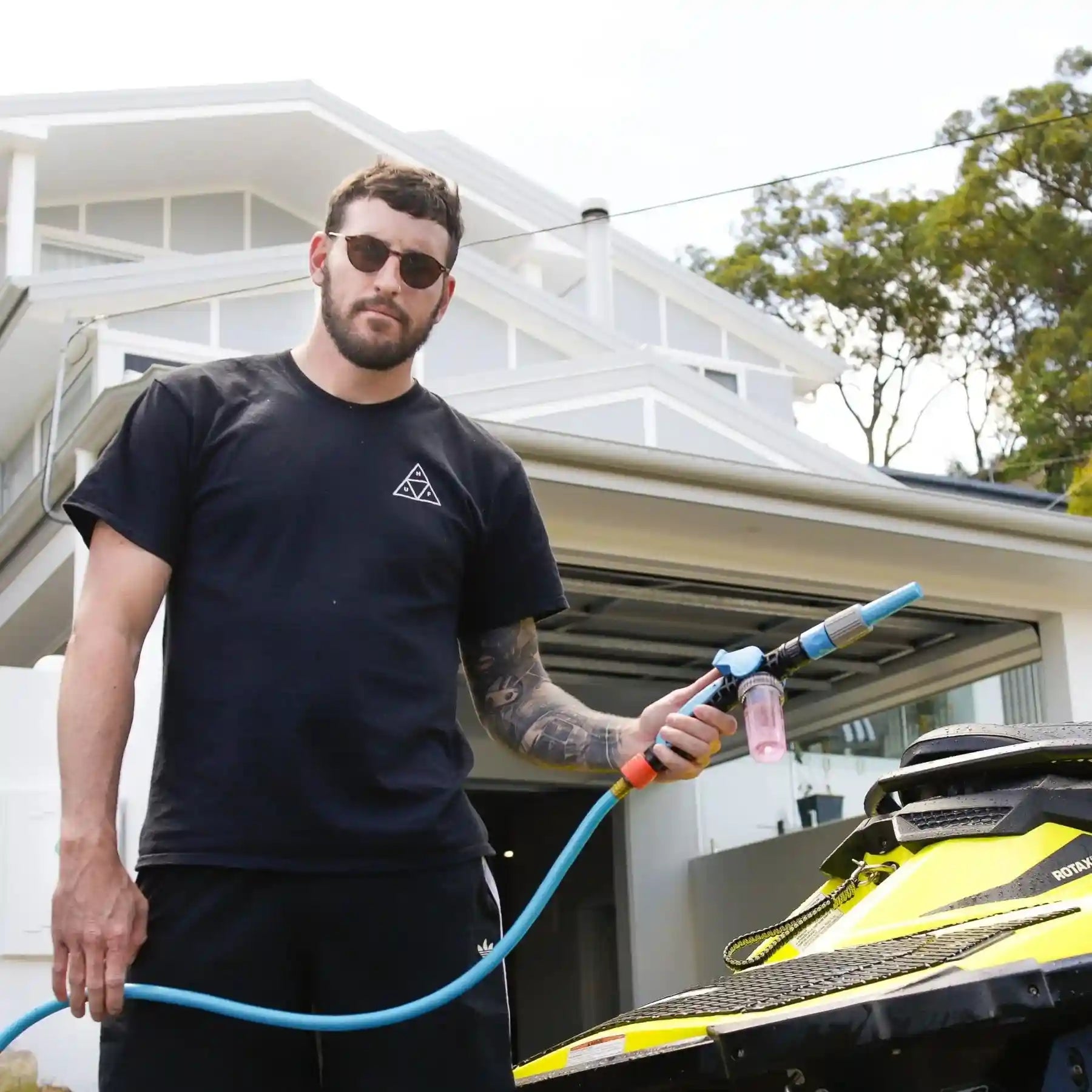 Man holding a pressure washer in front of a house