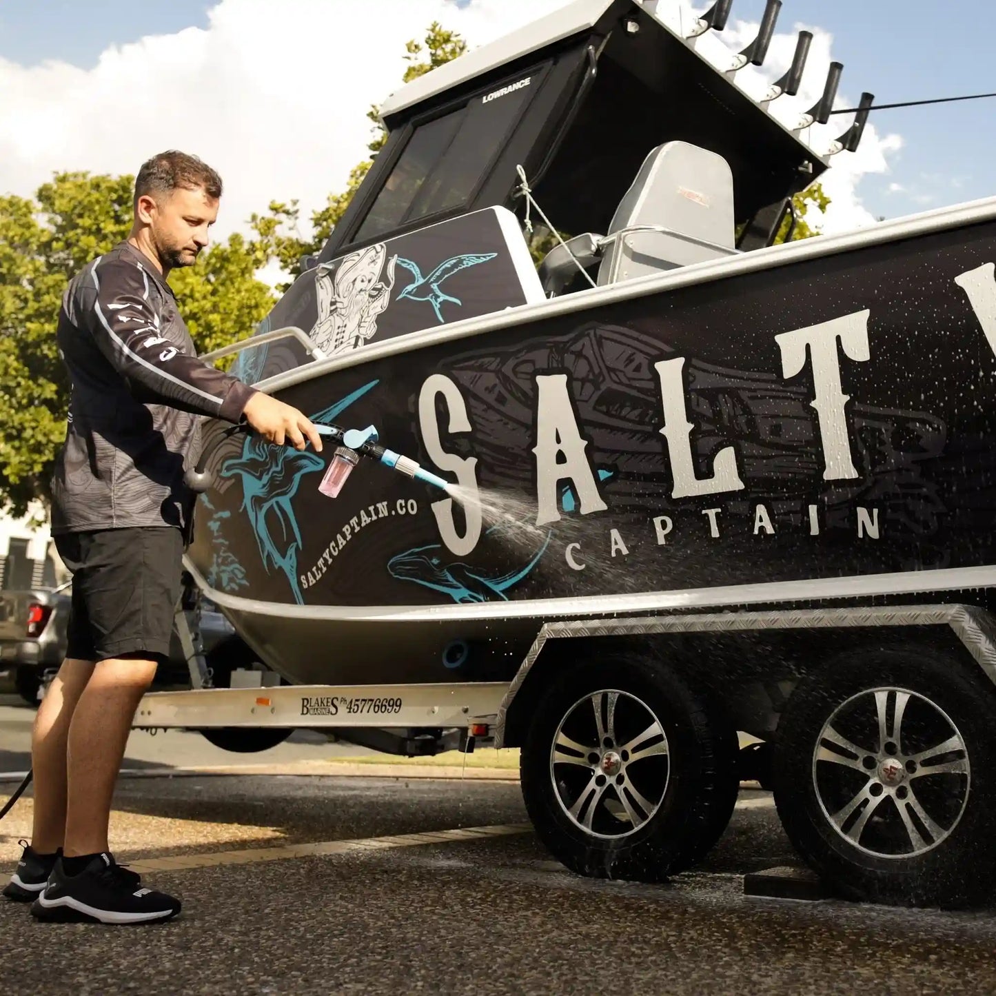 Man cleaning a boat with 'Salt Captain' branding on a trailer.