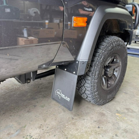 Close-up of a vehicle's mud flap with a tire and part of the car visible.