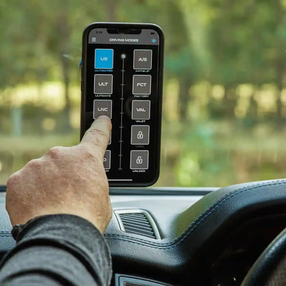 Hand using a smartphone app on a car dashboard with a blurred outdoor background