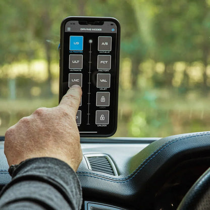 Hand using a smartphone app on a car dashboard with a blurred green outdoor background